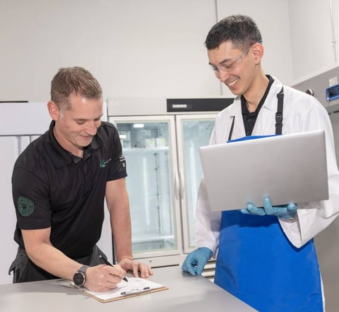 Lab employee holding laptop and van driver signing paper